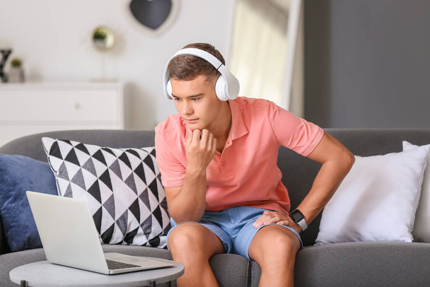 Teini-ikäinen poika kannettavan kuuntelee musiikkia kotona - Valokuva, kuva