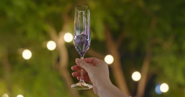 4K close-up vrouwen hand met champagne fluit. Nachtelijk zomerfeest, evenementbeelden - Video