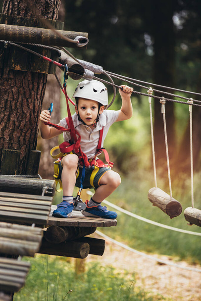Enfant heureux profitant d'une activité dans un parc d'aventure d'escalade un jour d'été - Photo, image