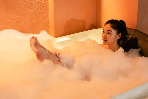 woman taking a bubble bath in the bathtub at the night - Foto, Imagem