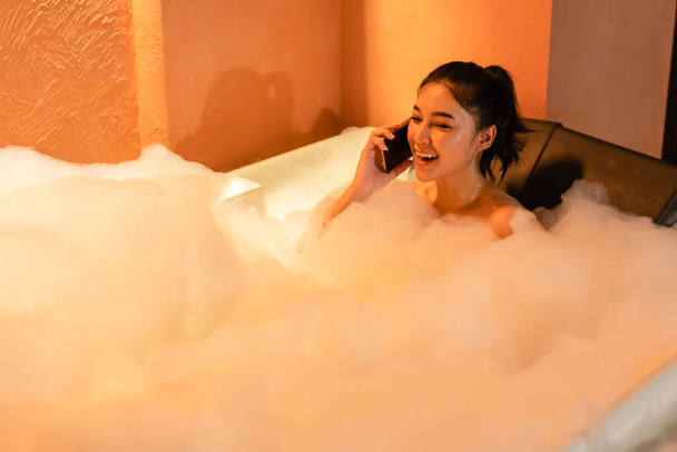 woman talking with mobile phone in the bathtub at the night - Foto, Imagem