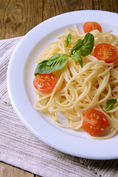Delicious spaghetti with tomatoes on plate on table close-up - Foto, Bild