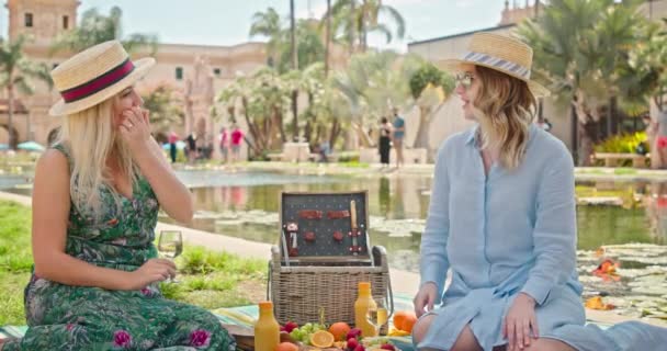 4K slow motion vrouwen vriendschap. Twee stijlvolle jonge vrouwen genieten van picknick in het park - Video