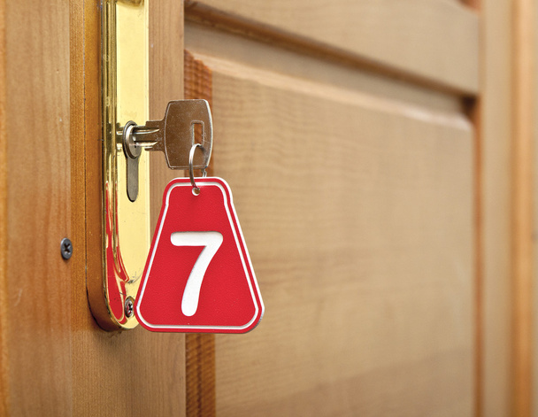 Puerta de madera y llave en cerradura con etiqueta numerada
 - Foto, Imagen