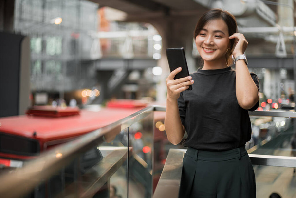 Šťastná asijská žena při pohledu na její telefon ve městě - Fotografie, Obrázek