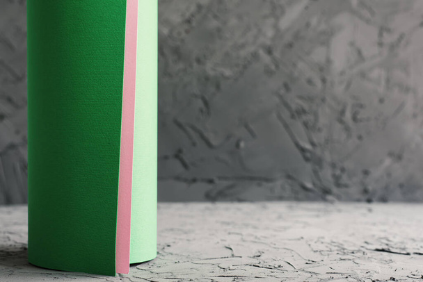 Бумажный рулон зеленого и розового цвета, бетонная стена и пол. Обои дизайн. Концепция реконструкции - Фото, изображение