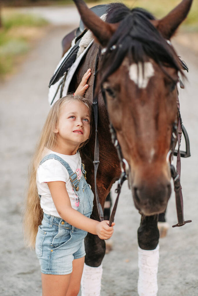 Amizade de uma criança com um cavalo. Tratar o autismo com um cavalo. Interação de uma menina com autismo e um cavalo. Caminhando uma criança com um cavalo no outono. - Foto, Imagem
