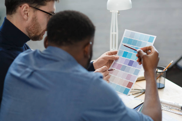 Multiracial engineer team working in office with color palette. Architects select colors for building using color swatches, sketching and planning construction project. Partners discussing at work - Foto, imagen