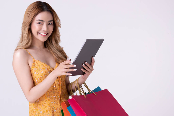 アジアの女性を保持ショッピングバッグとショッピングオンライン上のテブレット. - 写真・画像
