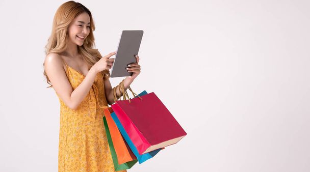 Asijské žena držení nákupní taška a nakupování on-line na teblet. - Fotografie, Obrázek