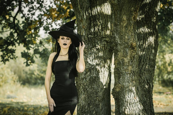 Halloween jelmez hölgyeknek. Gyönyörű fiatal nő fekete modern ruhában. Halloween művészet design. Sötét téma Halloween koncepció - Fotó, kép