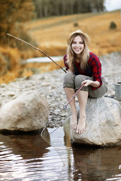 Beautiful young girl in autumn by the river with a fishing rod - Photo, Image