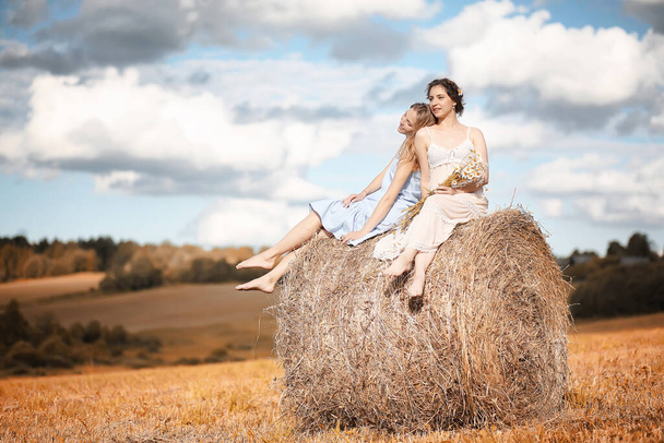 Две красивые девушки в платьях на осеннем поле весело провести время - Фото, изображение