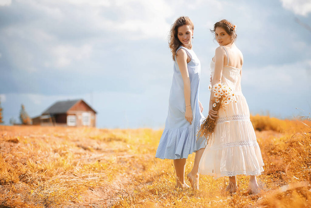 Deux belles filles en robes dans le domaine de l'automne s'amusent - Photo, image