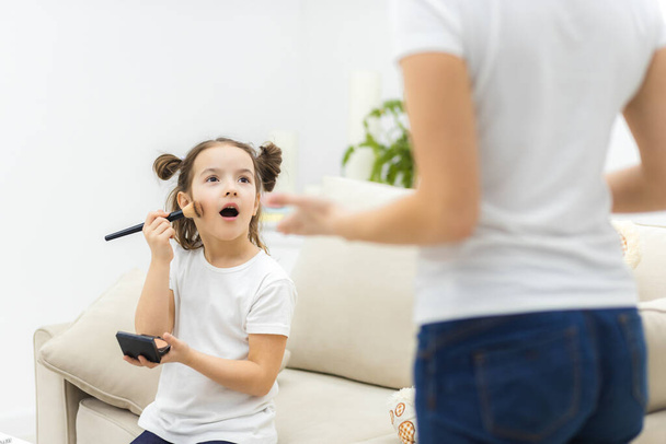Photo of little brunette little girl trying to apply make up, - Photo, Image