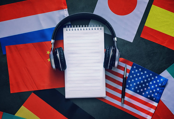 Fremdsprachen lernen. Audio Sprachkurse. Hintergrund: Länderflaggen und Kopfhörer auf dem Tisch. - Foto, Bild