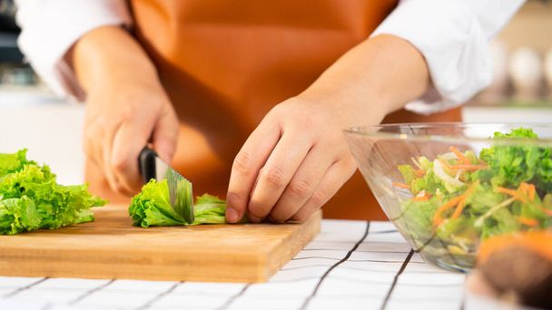 joven mujer asiática está preparando alimentos saludables ensalada de verduras mediante la corte de ingredientes en la tabla de cortar en la cocina ligera, cocina en casa y el concepto de alimentos saludables. - Foto, Imagen