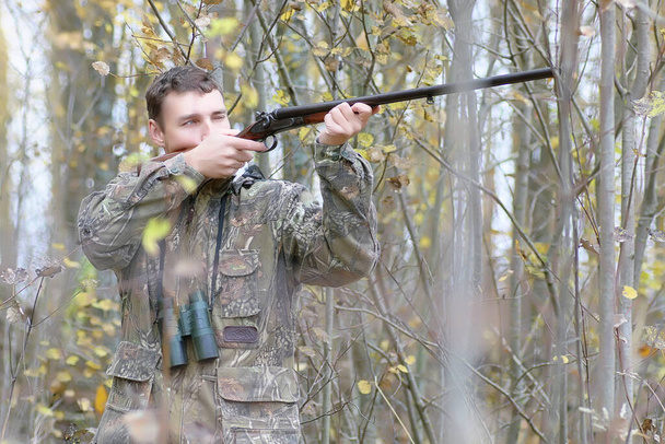 迷彩服の男と春の狩りの森のベルトの銃を持つ男 - 写真・画像
