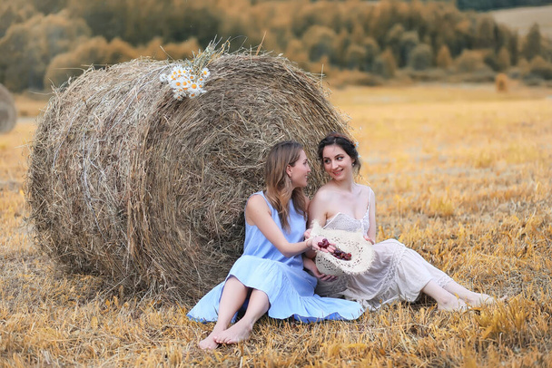 Δύο όμορφα κορίτσια σε φορέματα στο πεδίο φθινόπωρο με μούρα - Φωτογραφία, εικόνα