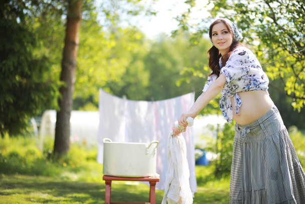 Έγκυος γυναίκα κρεμασμένα πλύσιμο ρούχα στο σχοινί για την ξήρανση - Φωτογραφία, εικόνα