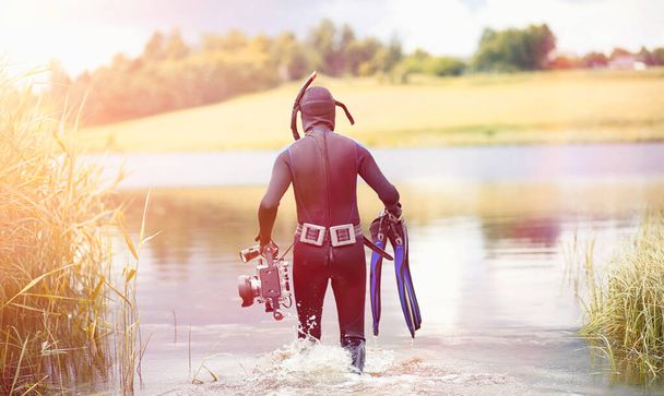 Ныряльщик с аквалангом в мокром костюме готовится погрузиться в пруд - Фото, изображение