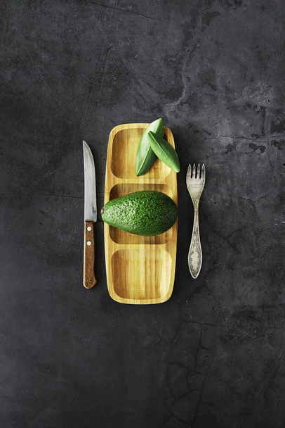 Avocado cooking recipes. Ripe green avocado on a wooden cutting board serving. - Foto, Imagem