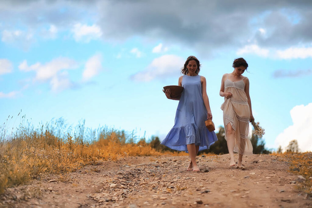 Две красивые девушки в платьях на осеннем поле с ягодами - Фото, изображение