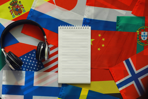 Idegen nyelveket tanulni. Hangnyelvi kurzusok. Háttér országok zászlók és fülhallgatók az asztalon. - Fotó, kép