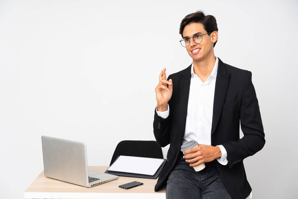 Empresário em seu escritório sobre fundo branco isolado com dedos cruzando - Foto, Imagem