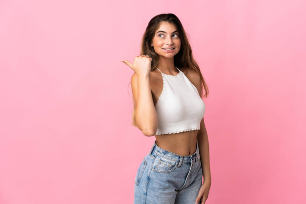 Young caucasian woman isolated on pink background pointing to the side to present a product - Photo, Image