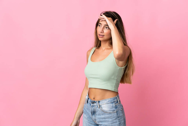 Young caucasian woman isolated on pink background with surprise expression while looking side - Foto, imagen
