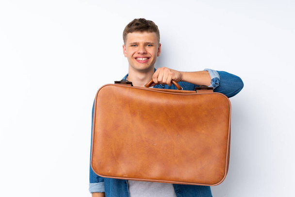 Young handsome man over isolated white background holding a vintage briefcase - Zdjęcie, obraz