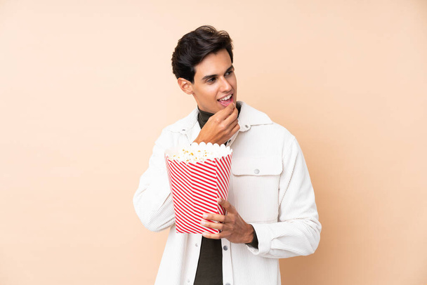 Man over geïsoleerde achtergrond met een grote emmer popcorn - Foto, afbeelding