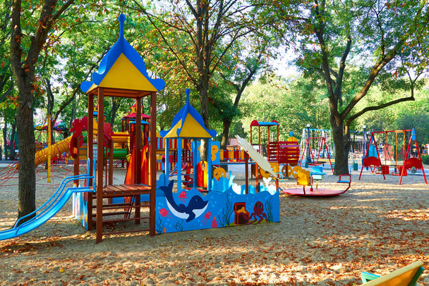 Kinderspielplatz im Stadtpark am frühen Morgen, verschiedene Schaukeln und Karussells - Foto, Bild