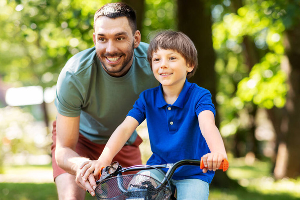 padre enseñando a su hijo a montar en bicicleta en el parque - Foto, imagen