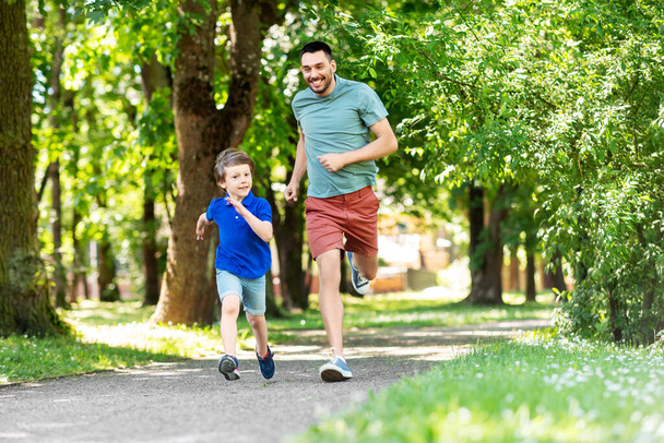 happy father and son compete in running at park - 写真・画像