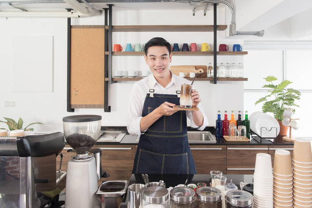 Barista man in smiling face show ice coffee in coffee shop, look at camera, feeling happiness - Photo, Image