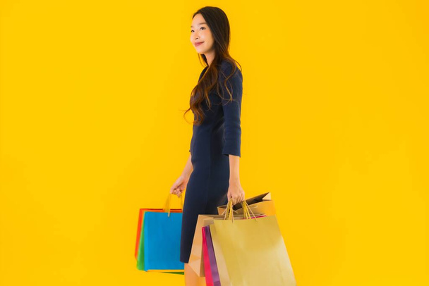Portrait belle jeune femme asiatique avec sac à provisions coloré sur fond jaune isolé - Photo, image