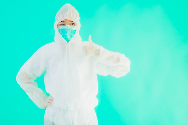 Portré gyönyörű fiatal ázsiai orvos nő visel ppe vagy egyéni védőfelszerelés védelme érdekében a coronavirus vagy covid19 üres kártya fehér tábla kék izolált háttér - Fotó, kép