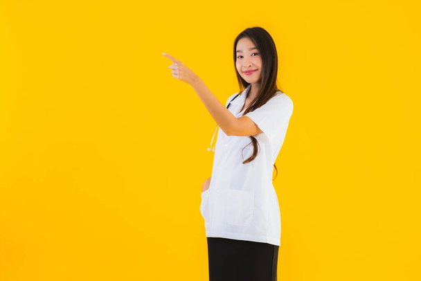 Retrato hermosa joven asiática médico mujer sonrisa feliz trabajo en hospital y clínica en amarillo aislado fondo
 - Foto, imagen