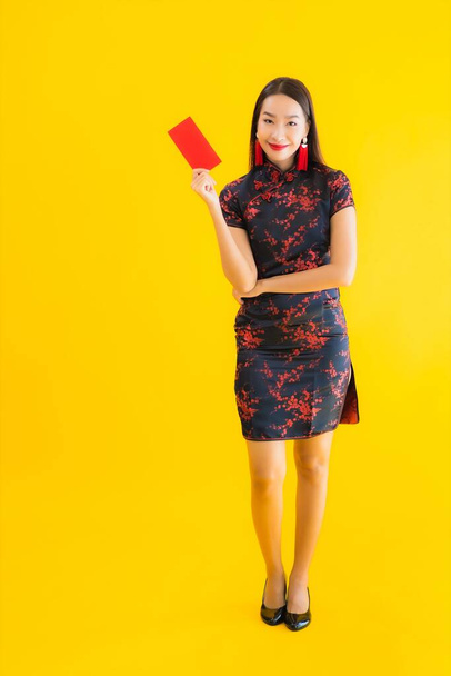 Retrato bela jovem mulher asiática usar vestido chinês com Ang Pao ou carta vermelha com dinheiro para o conceito de ano novo chinês no fundo isolado amarelo
 - Foto, Imagem