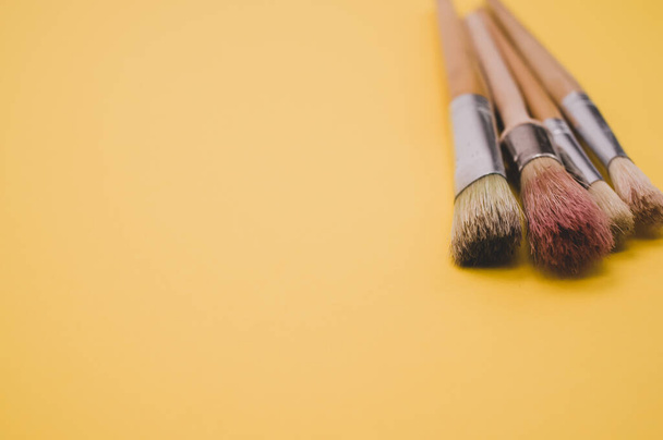 A closeup high angle shot of paintbrushes on a yellow surface - Zdjęcie, obraz