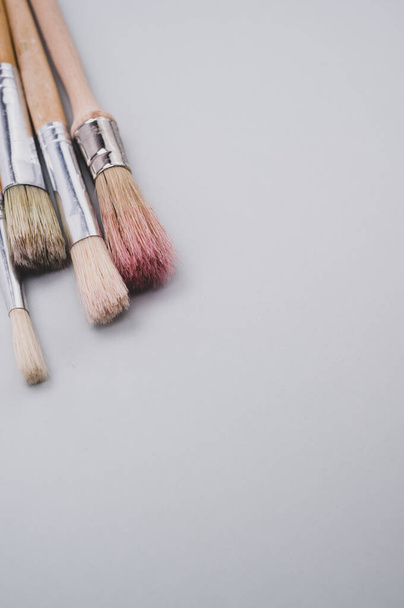 A vertical closeup focus shot of paintbrushes on a gray surface - Foto, afbeelding