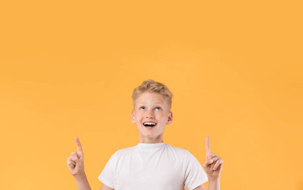 Usmívající se chlapec ukazuje prstem nahoru na kopírovací prostor - Fotografie, Obrázek