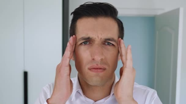 Tired office worker suffering from headache. Stressed business man in white shirt feeling headache and massaging head to relax and reduce pain, indoor, close up. - Footage, Video
