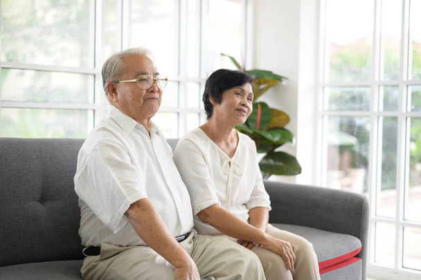 Elderly Asian couple watching television sitting on a sof - Фото, зображення