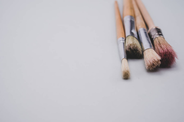 A closeup high angel shot of paintbrushes on a gray surface - Fotó, kép