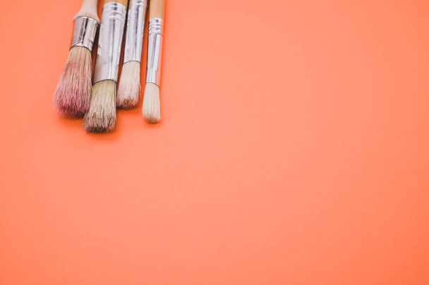 A closeup high angle shot of paintbrushes on an orange surface - Foto, afbeelding