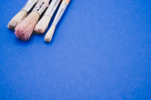 A closeup high angle shot of paintbrushes on a blue surface - Zdjęcie, obraz