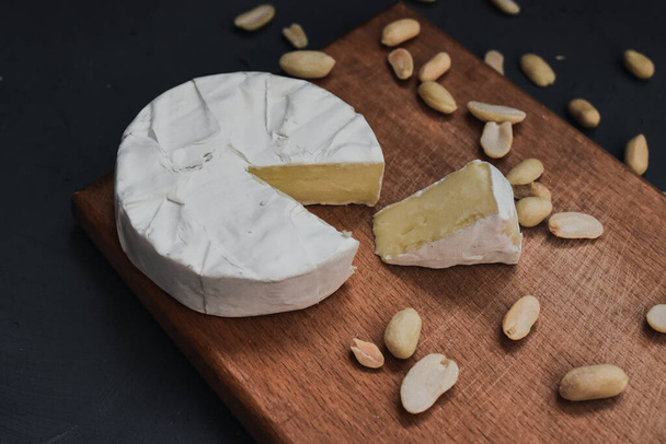 сыр камамбер с плесенью и орехами на деревянной доске - Фото, изображение